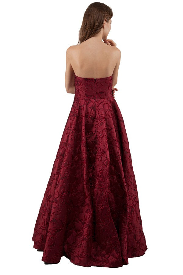 Burgundy strapless formal dress in brocade fabric.