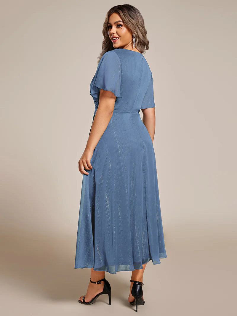 Dusty blue plus size wedding guest dress with short sleeve and ruffle front.