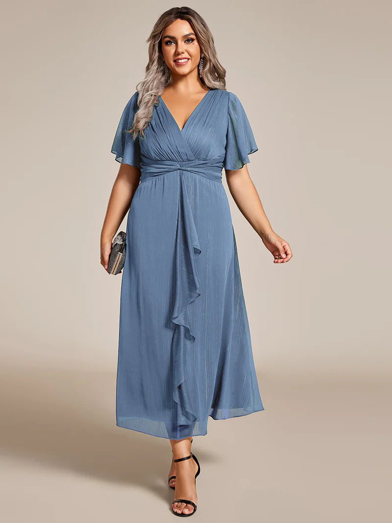 Dusty blue plus size wedding guest dress with short sleeve and ruffle front.