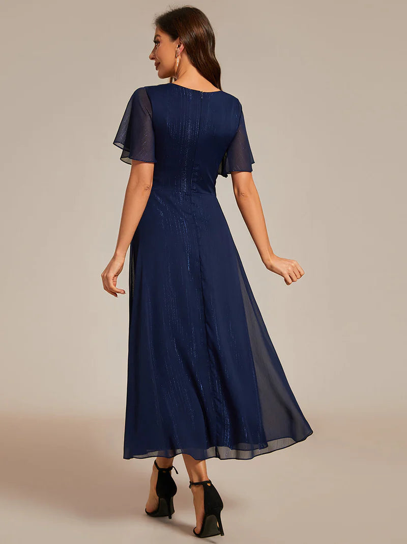Navy blue plus size wedding guest dress with short sleeve and ruffle front.