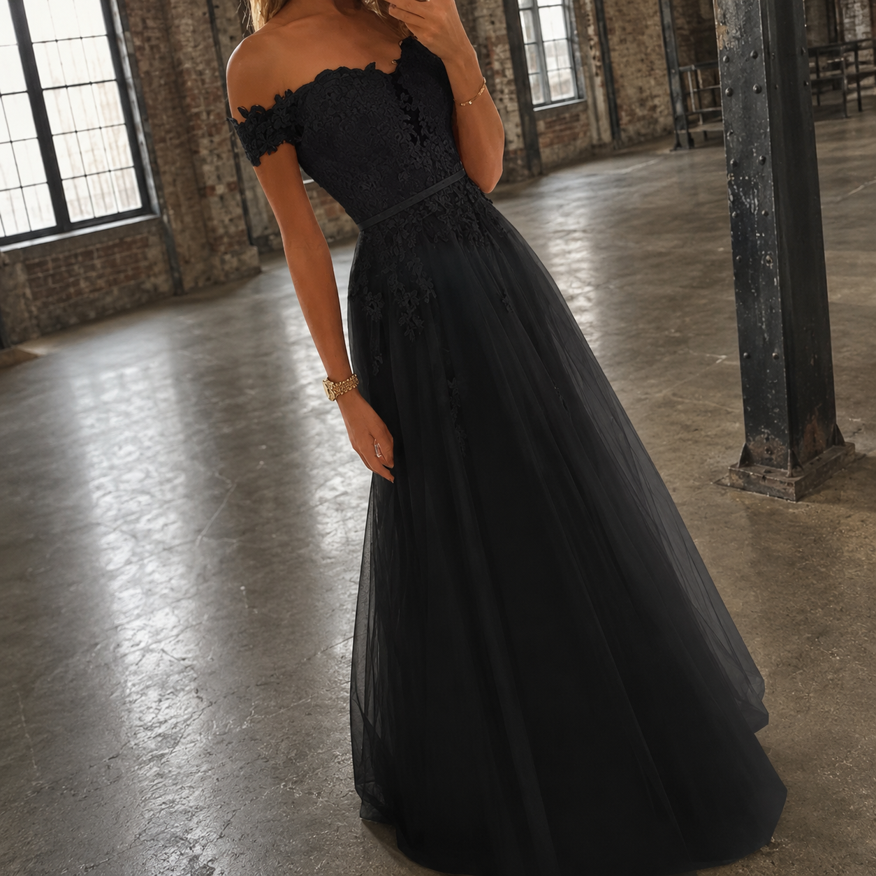 Black tulle formal dress has an off the shoulder design wit tulle applique detail.