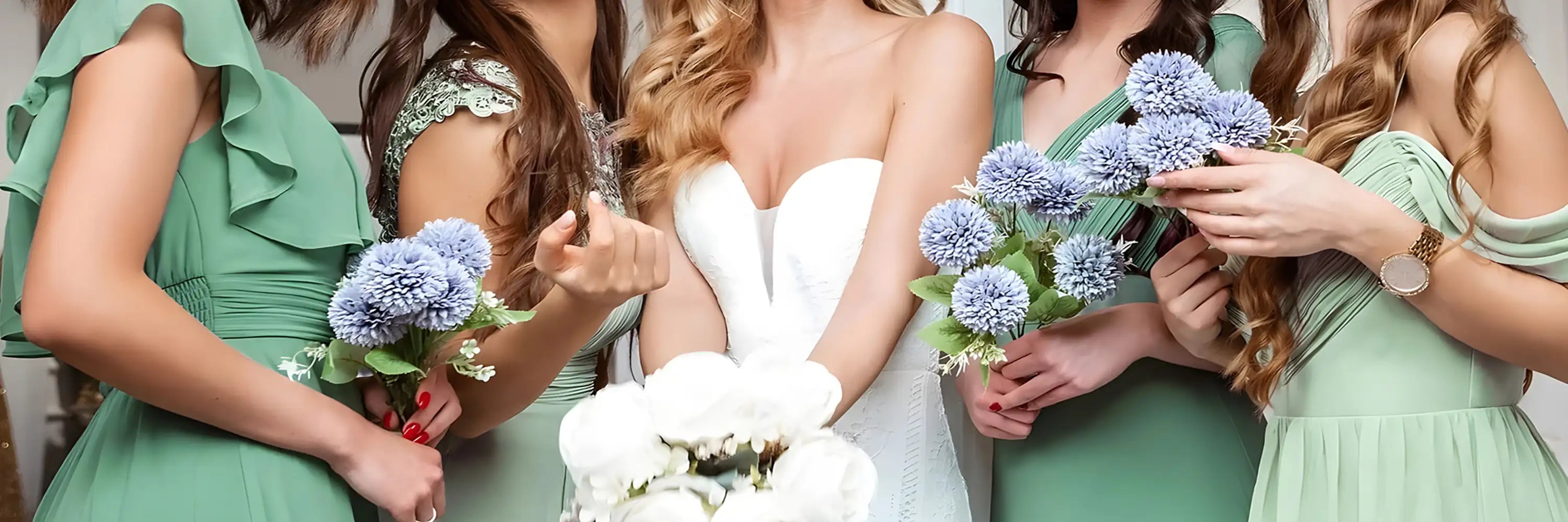 Bride in a white dress with green bridesmaids dresses around holding flowers.