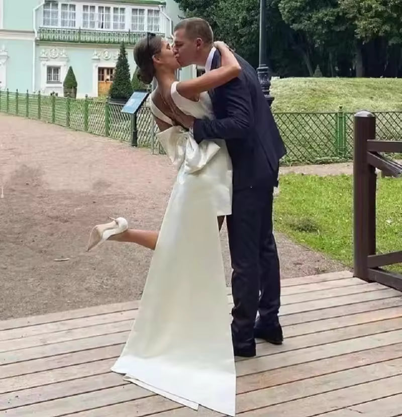 Ivory short satin wedding dress with bow and train.