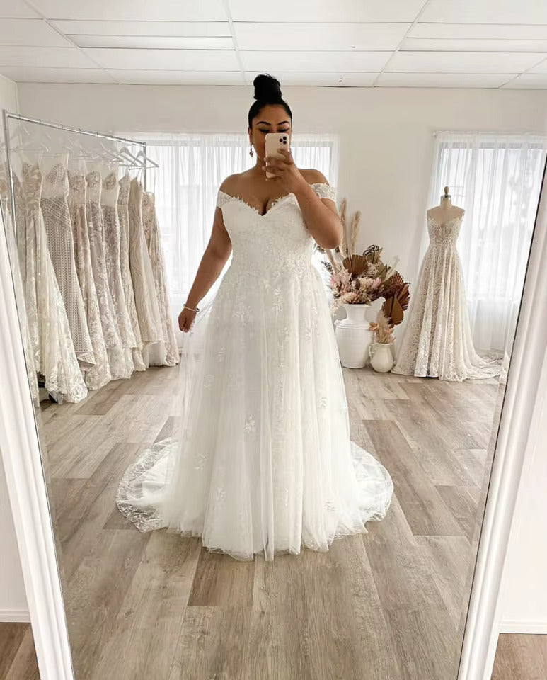 White plus size wedding dress off shoulder style with lace up back and applique tulle.