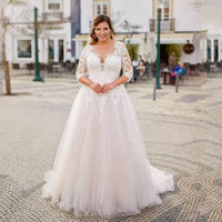 White plus size wedding dress with three quarter lace sleeves and tulle skirt.