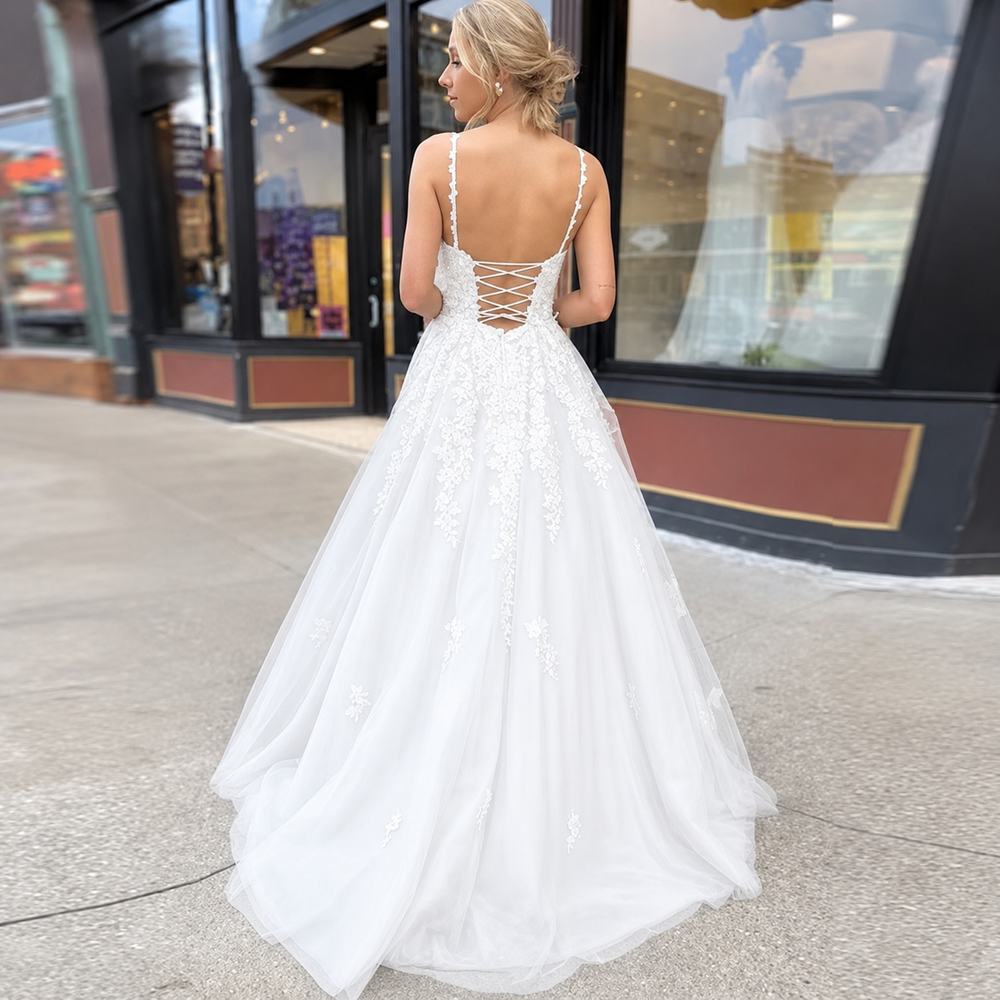 White tulle wedding dress with applique detail, spaghetti straps and lace up back.