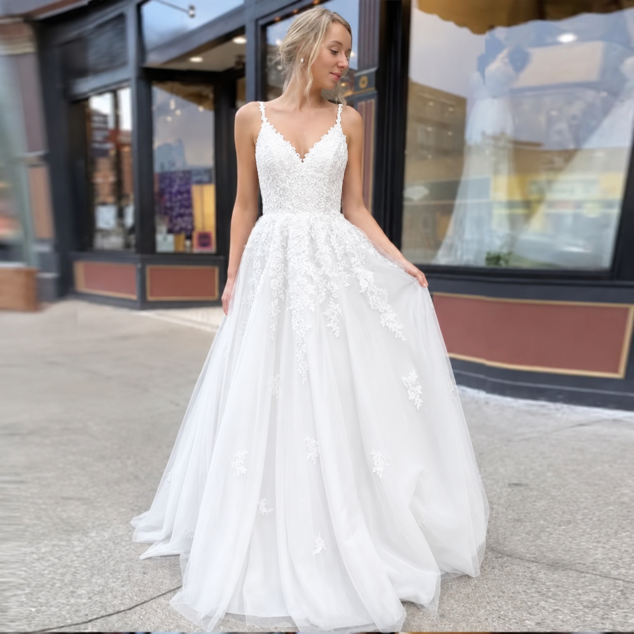 White tulle wedding dress with applique detail, spaghetti straps and lace up back.