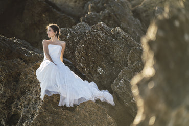 selective focus shot brunette female white dress posing rocks