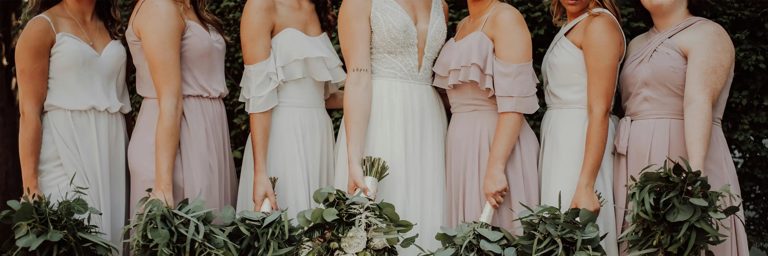 Bride with bridesmaids wearing mismatched blush and white bridesmaid dresses holding greenery bouquets